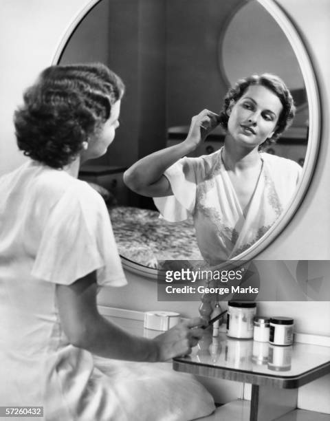 woman doing hair in front of mirror, (b&w) - 1940s bedroom stock pictures, royalty-free photos & images