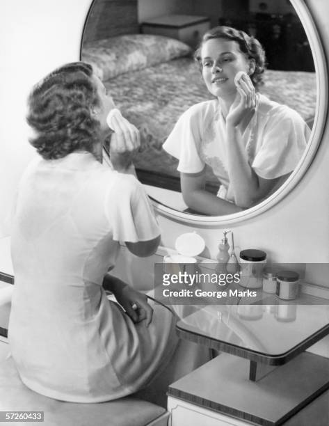 woman applying powder with powder puff in front of mirror, (b&w) - 1940s bedroom stock pictures, royalty-free photos & images