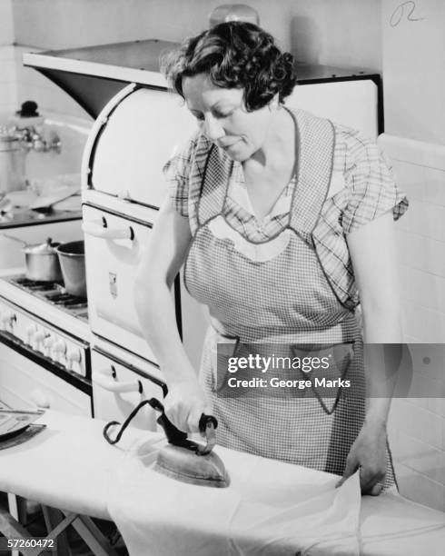 woman ironing in kitchen, (b&w) - 1950 females only housewife stockfoto's en -beelden