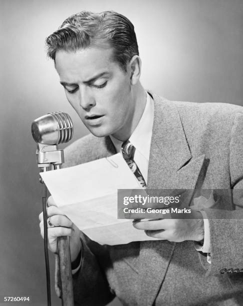 elegant man talking into microphone in studio, (b&w) - 1950s man stockfoto's en -beelden