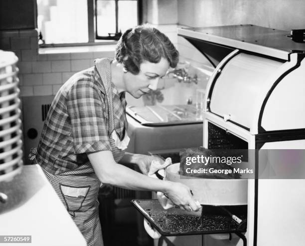 housewife removing turkey from oven, (b&w) - housewife stock pictures, royalty-free photos & images