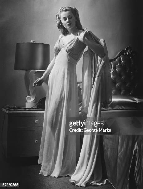 young woman standing by bed wearing dressing gown, (b&w) - 1940s bedroom stock pictures, royalty-free photos & images