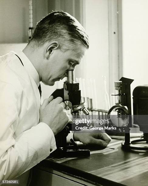male doctor using microscope in surgery, (b&w) - styles stock pictures, royalty-free photos & images