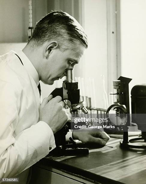 male doctor using microscope in surgery, (b&w) - vintage stock stock pictures, royalty-free photos & images