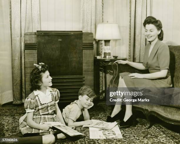 family at home, children (6-7) (10-11) playing on carpet, mother sitting on sofa, (b&w) - 1940s woman stock pictures, royalty-free photos & images