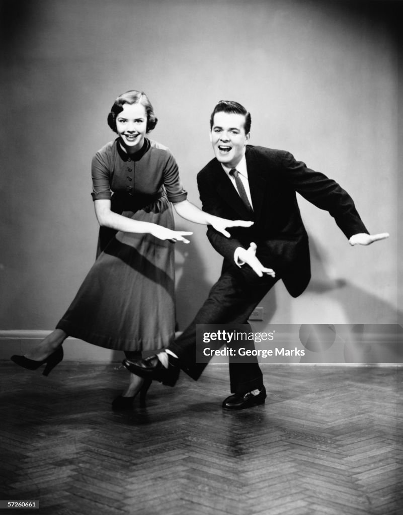 Young couple dancing in empty room, (B&W)