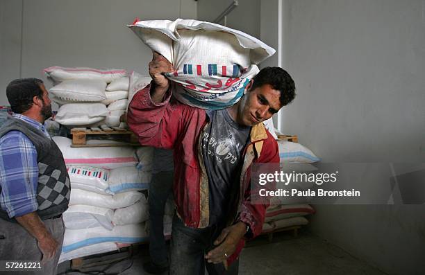 Palestinian man carries flour out from the World Food Program warehouse during food distribution April 5, 2006 in Gaza City, the Gaza Strip....