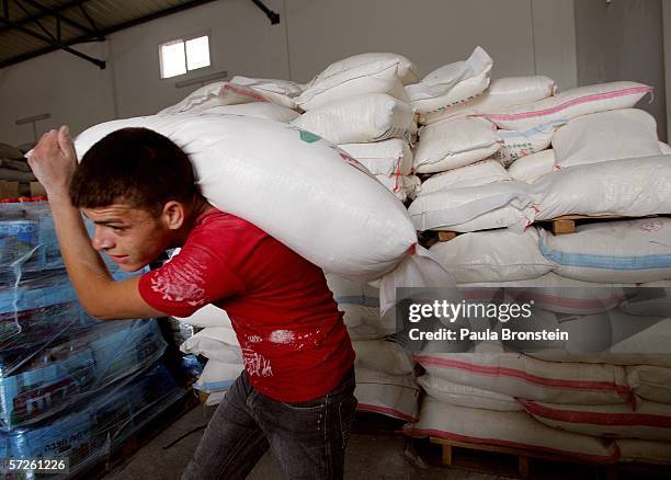 Palestinian man carries flour out from the World Food Program warehouse during food distribution April 5, 2006 in Gaza City, the Gaza Strip....