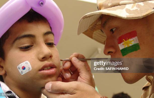 South Korean soldier paints the Korean flag on the face of an Iraqi Kurdish orphan during a ceremony in the northern city of Arbil, 06 April 2006,...