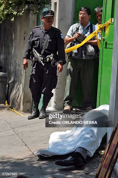 Un agente de la Policia Nacional Civil observa junto a un reportero grafico el cadaver del diputado Mario Pivaral, asesinado en la puerta de la sede...