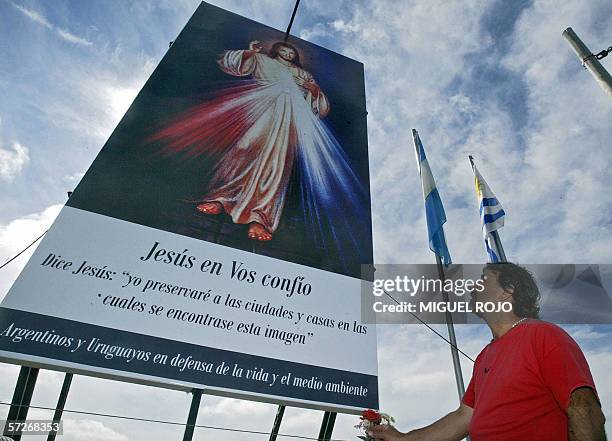 Gualeguaychu, URUGUAY: Un argentino coloca una flor junto a un cartel que vincula a Jesus con el medio ambiente en el campamento instalado por...
