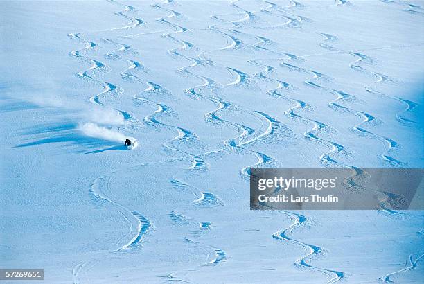 a person skiing in snow covered with skiing tracks. - alpine skiing stock pictures, royalty-free photos & images