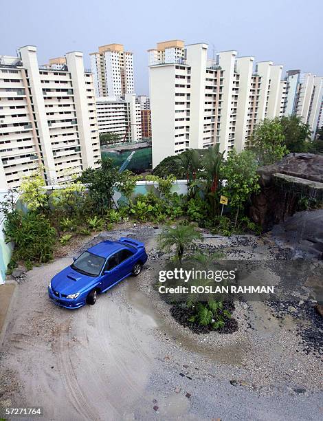 Driver steers a Subaru rally car on the roof-top multi-terrain test track of the Motor Image service centre which is designed and decorated with a...