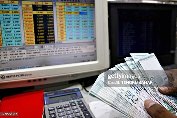 Kuala Lumpur, MALAYSIA: A money changer counts RM50 ringgit bills at a currency exchange in Kuala Lumpur, 07 April 2006. The Malaysian ringgit on 04...