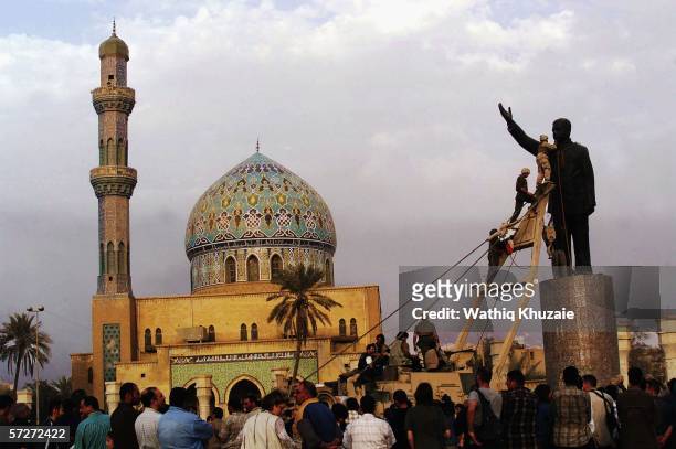 Marines climb up to topple a statue of Iraqi dictator Saddam Hussein on April 9, 2003 at al-Fardous square in Baghdad, Iraq.. The third year...