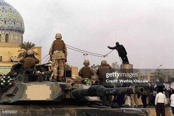 Marines and Iraqis are seen on April 9, 2003 as the statue of Iraqi dictator Saddam Hussein is toppled at al-Fardous square in Baghdad, Iraq. The...