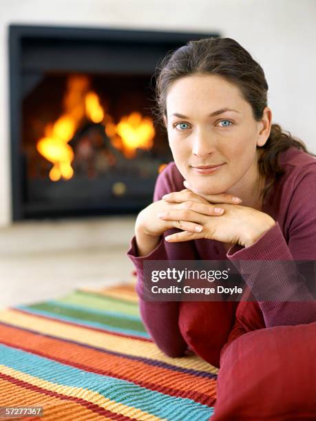 portrait of a young woman lying down with her hands on chin - open haard stockfoto's en -beelden