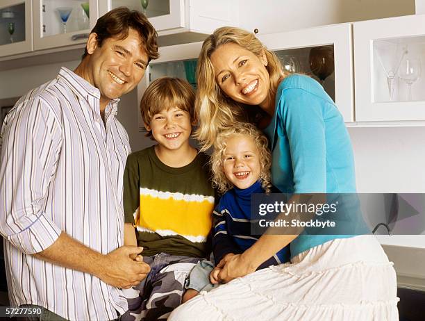 portrait of parents with their son and daughter, smiling - front view portrait of four children sitting on rock stock-fotos und bilder