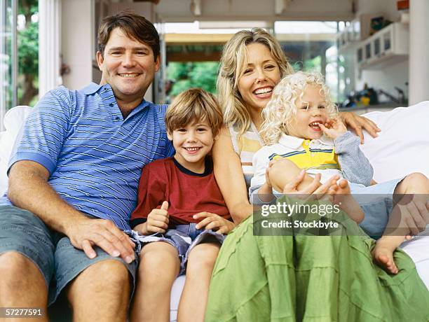 portrait of parents with their son and daughter, smiling - front view portrait of four children sitting on rock stock-fotos und bilder