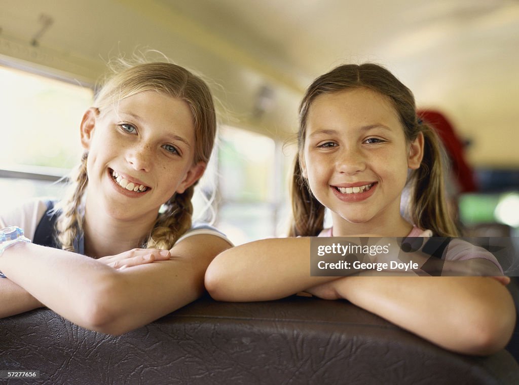 Portrait of two girls leaning over a seat