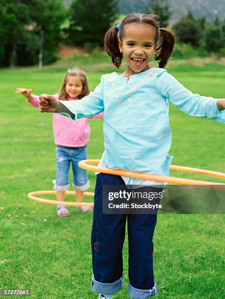 portrait of two girls playing with plastic hoops - only girls fotografías e imágenes de stock