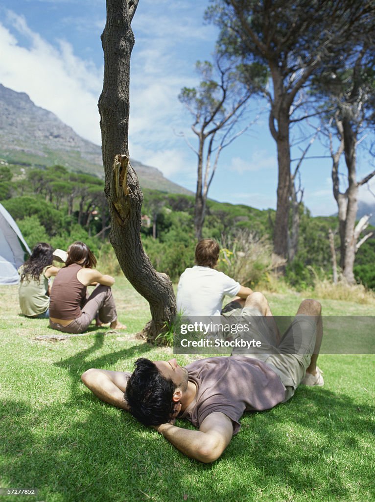 Rear view of young man lying on the ground with his arms behind his head