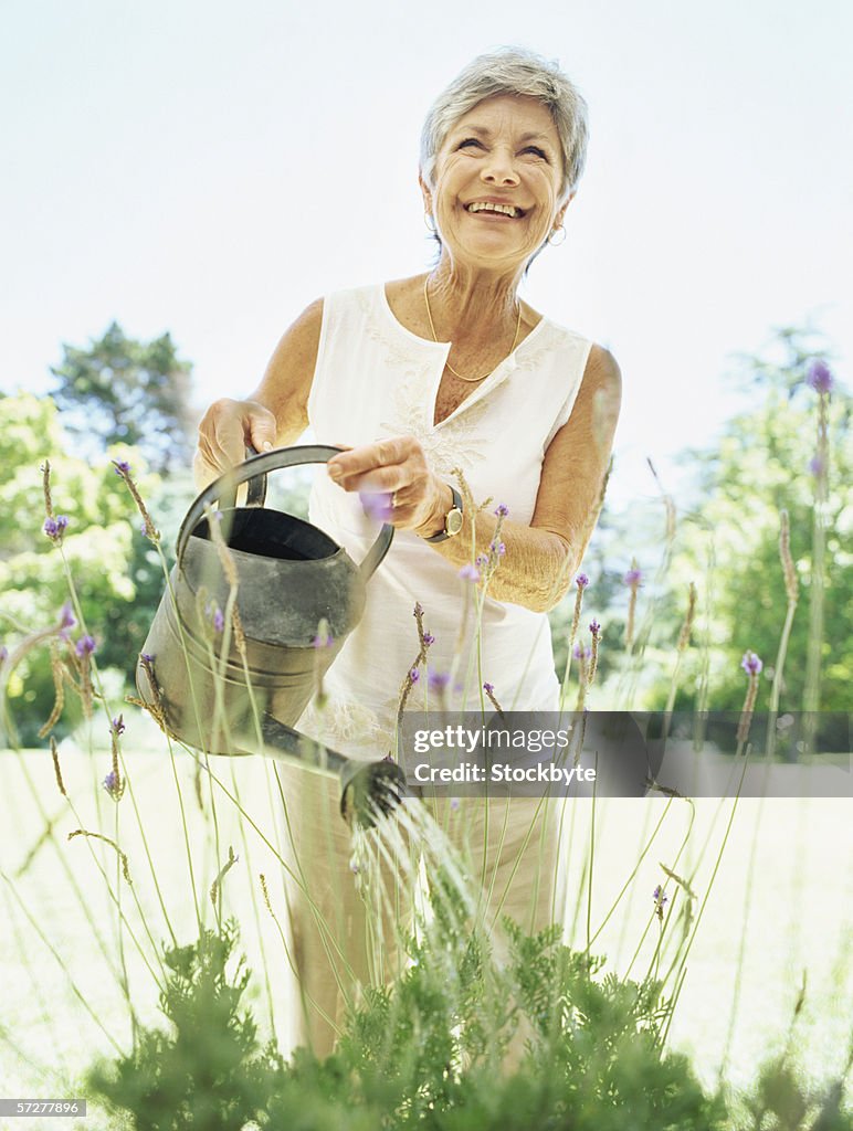 Senior woman watering plants with a watering can