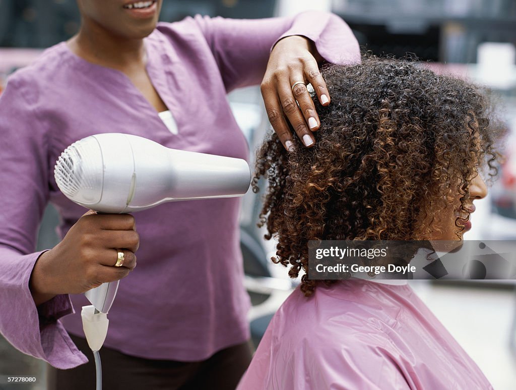 Side profile of a woman having her hair dried with a hair dryer