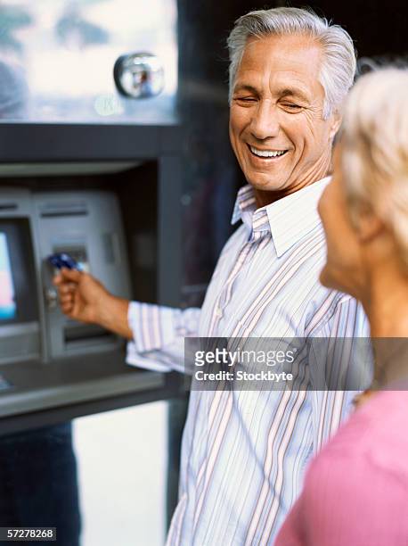 side view of a mature couple at an atm - man atm smile stock pictures, royalty-free photos & images