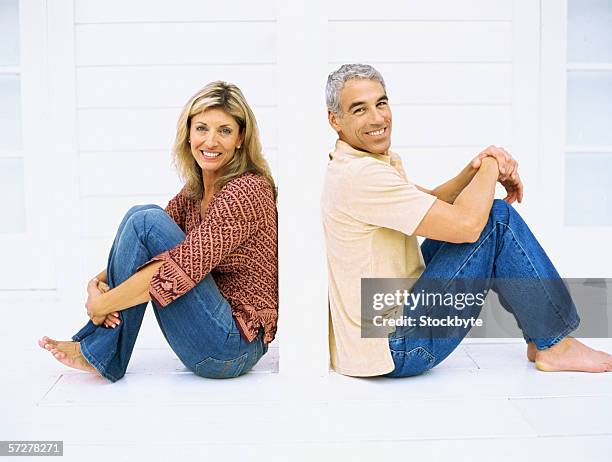 side view of a mature couple sitting and smiling - jeans barefoot stock pictures, royalty-free photos & images