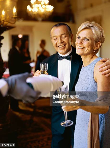 side view of a mature couple smiling and holding champagne flutes - abendkleid stock-fotos und bilder