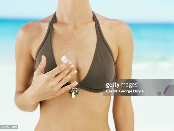 mid section view of a woman applying moisturizer to her body - escote fotografías e imágenes de stock