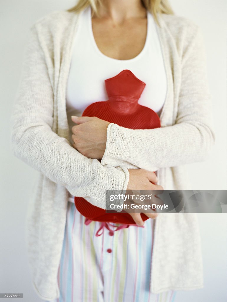 Mid section view of a woman holding hot water bottle