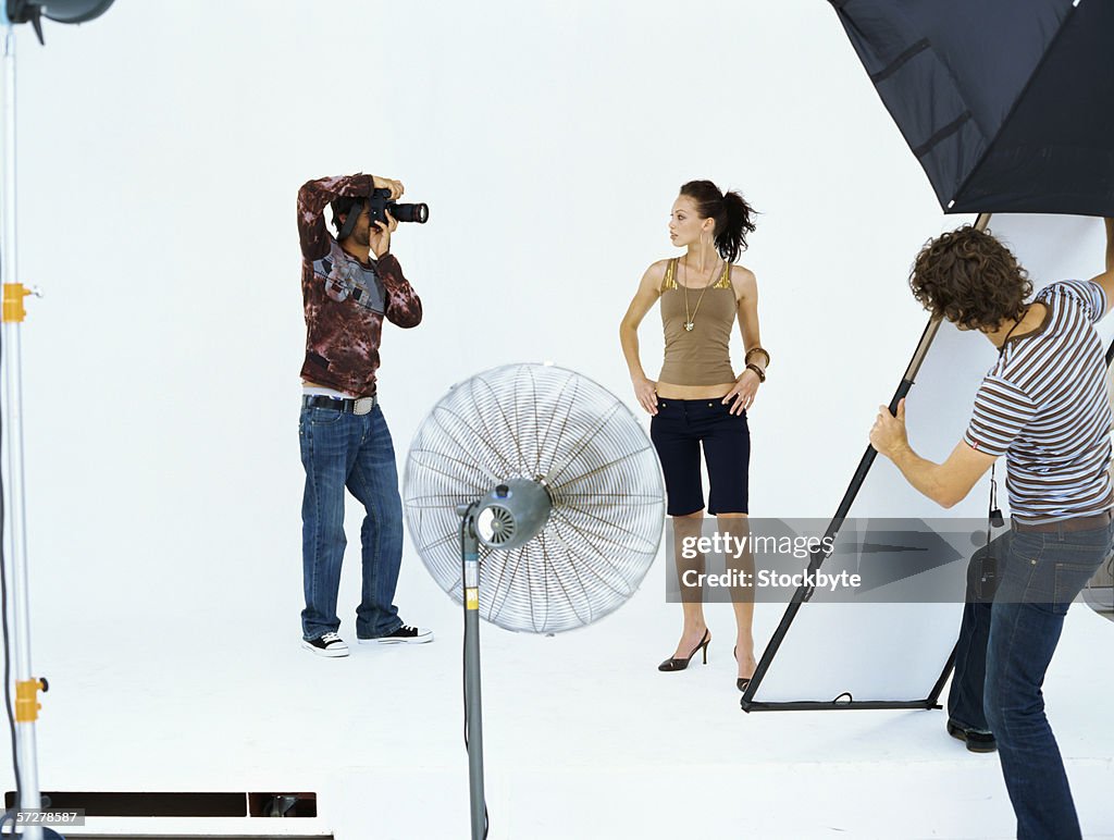 Photographer taking a photograph of a young woman in a studio
