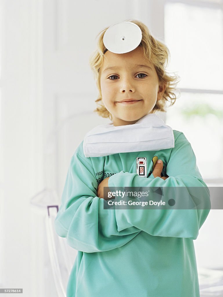 Portrait of a  boy pretending to be a doctor, standing with his arms folded