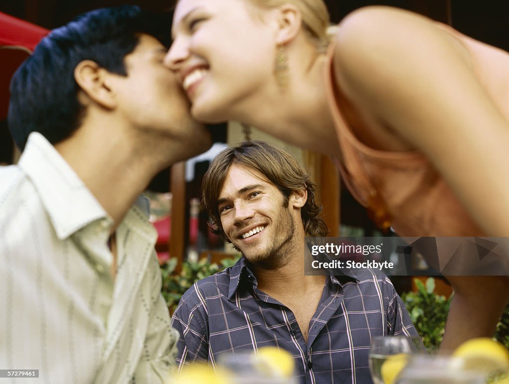 Close-up of a young man looking at a young couple kissing