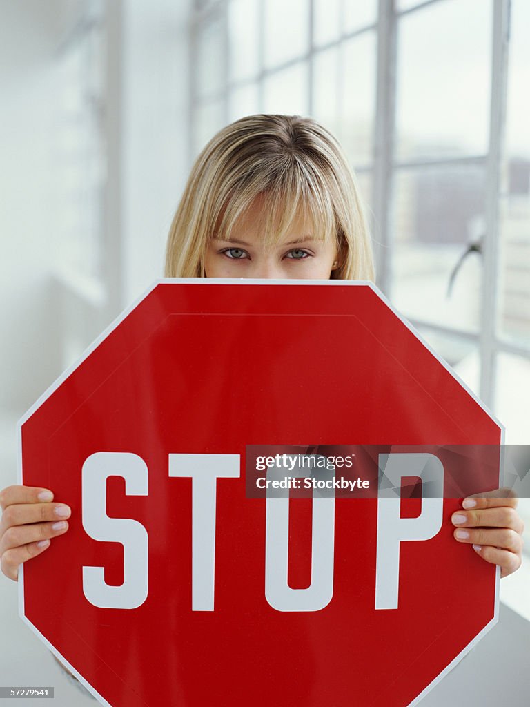 Close-up of a young woman holding a stop sign