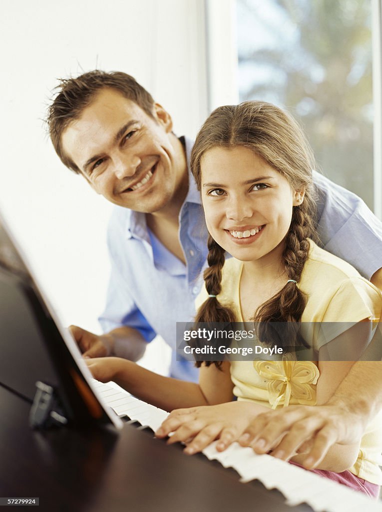 Girl sitting at a piano with her music teacher