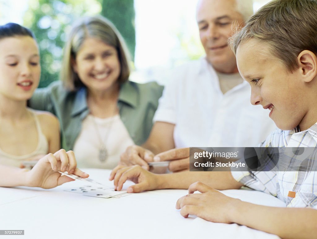 Grandchildren playing cards with their grandparents