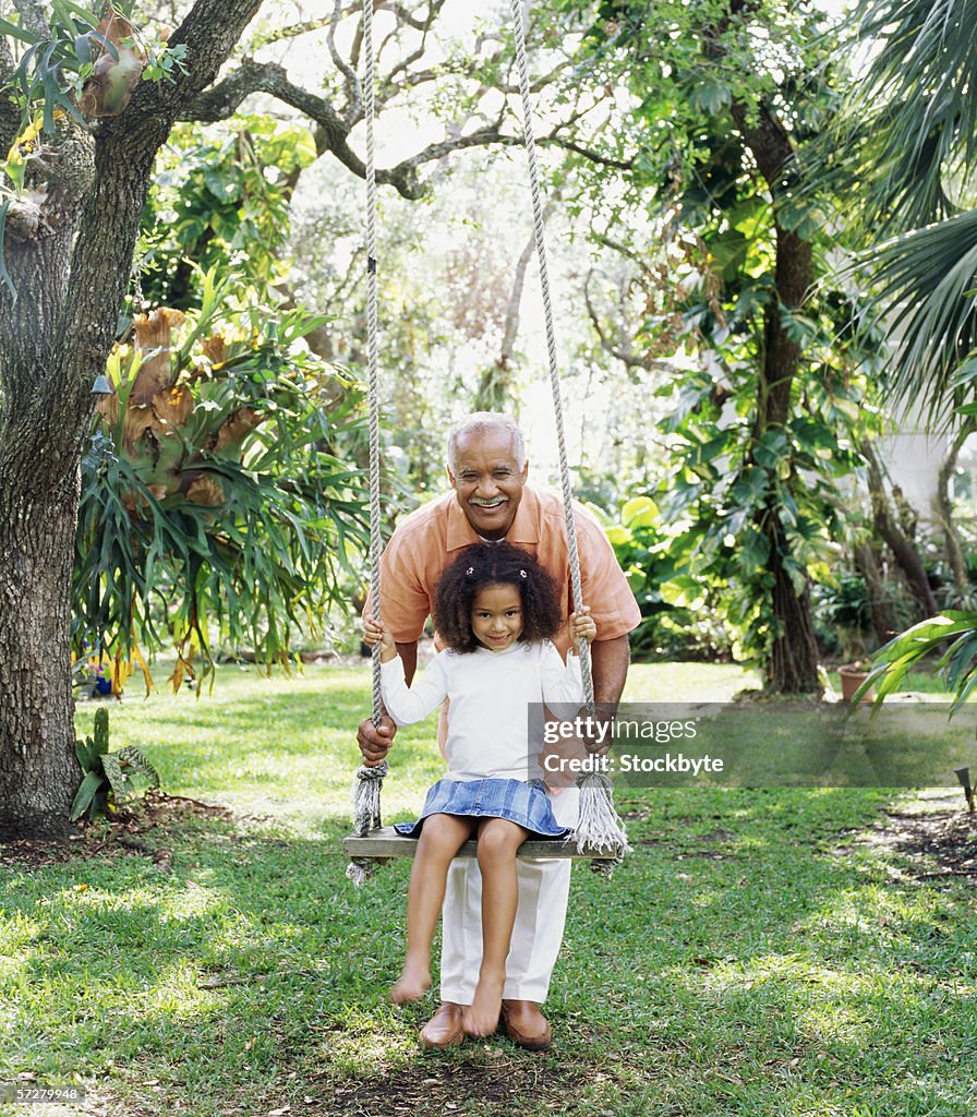 Grandfather swinging his granddaughter in a park