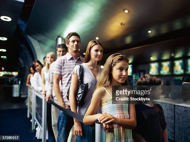 large group of people standing in a queue inside a cinema - kids lining up stock pictures, royalty-free photos & images