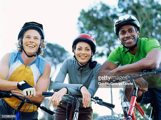 low angle view of two young men and a young woman on mountain bikes - black helmet stock pictures, royalty-free photos & images