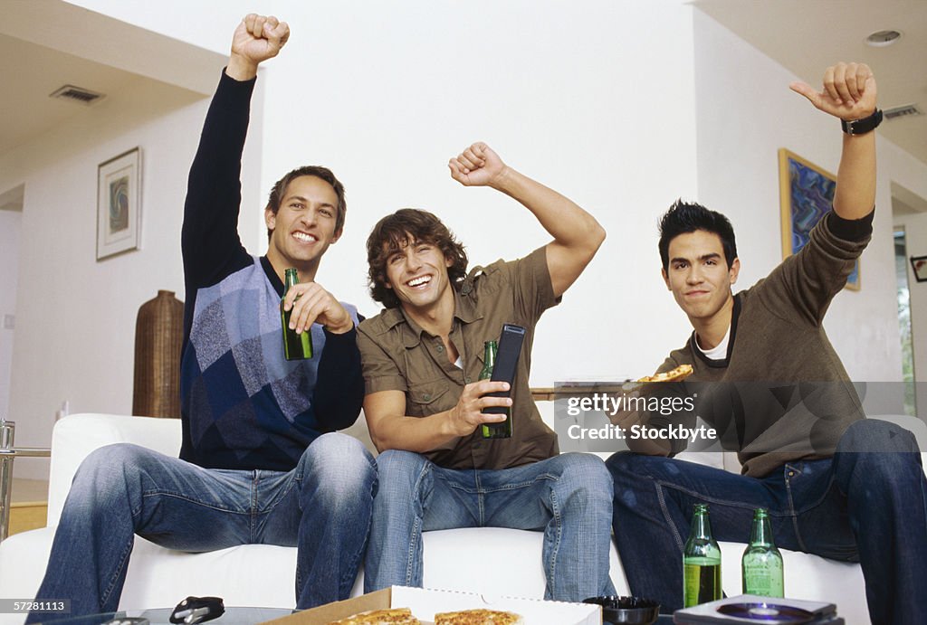 Three men watching sport, eating pizza and drinking beer