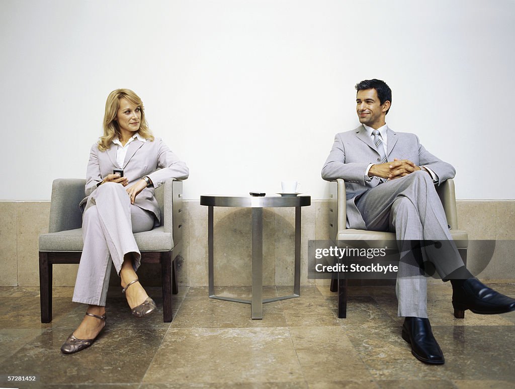 Businessman and businesswoman sitting on armchairs