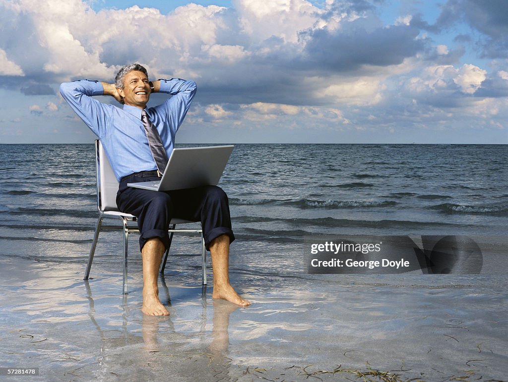 Businessman sitting on a chair on the beach with his hands behind his head