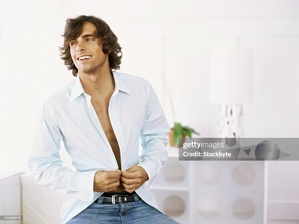 Close-up of a young man buttoning his shirt