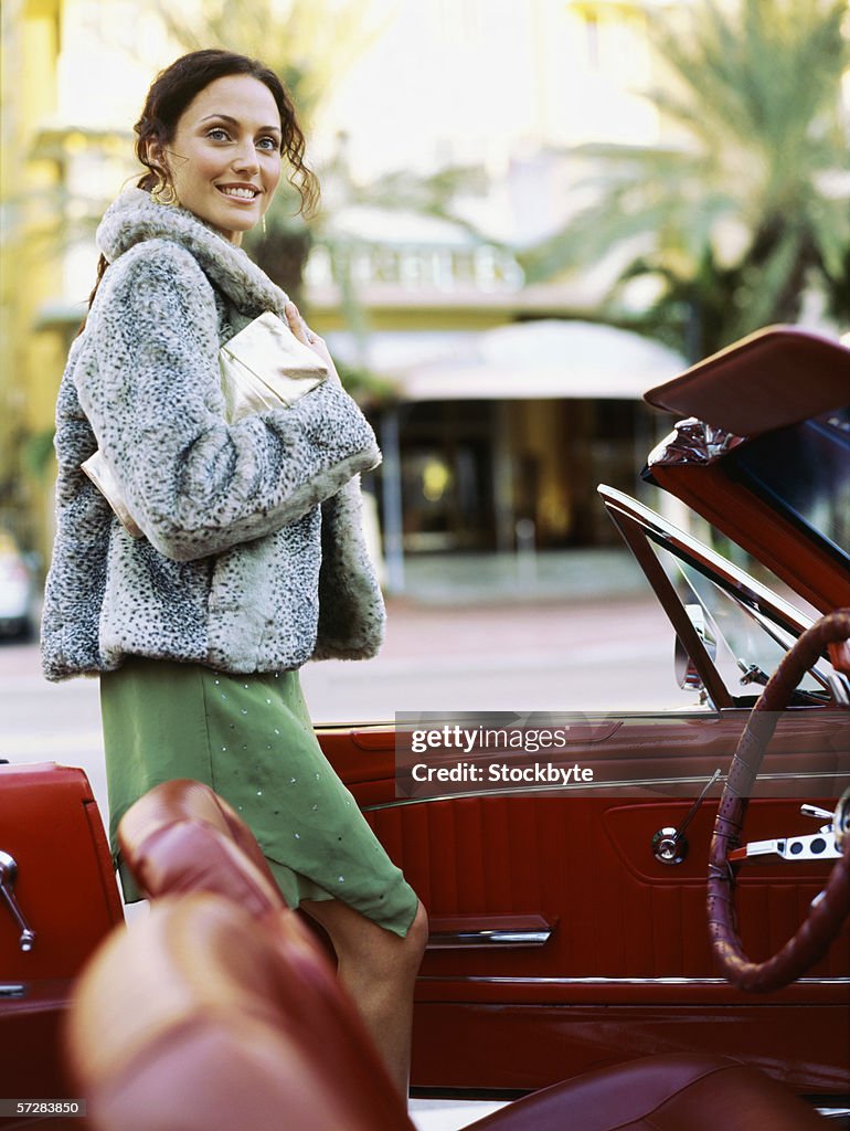 Side view of a young woman getting out of a car