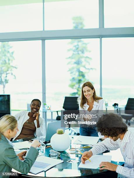 three businesswomen and a businessman in an  office working at a round table - round table discussion stock pictures, royalty-free photos & images