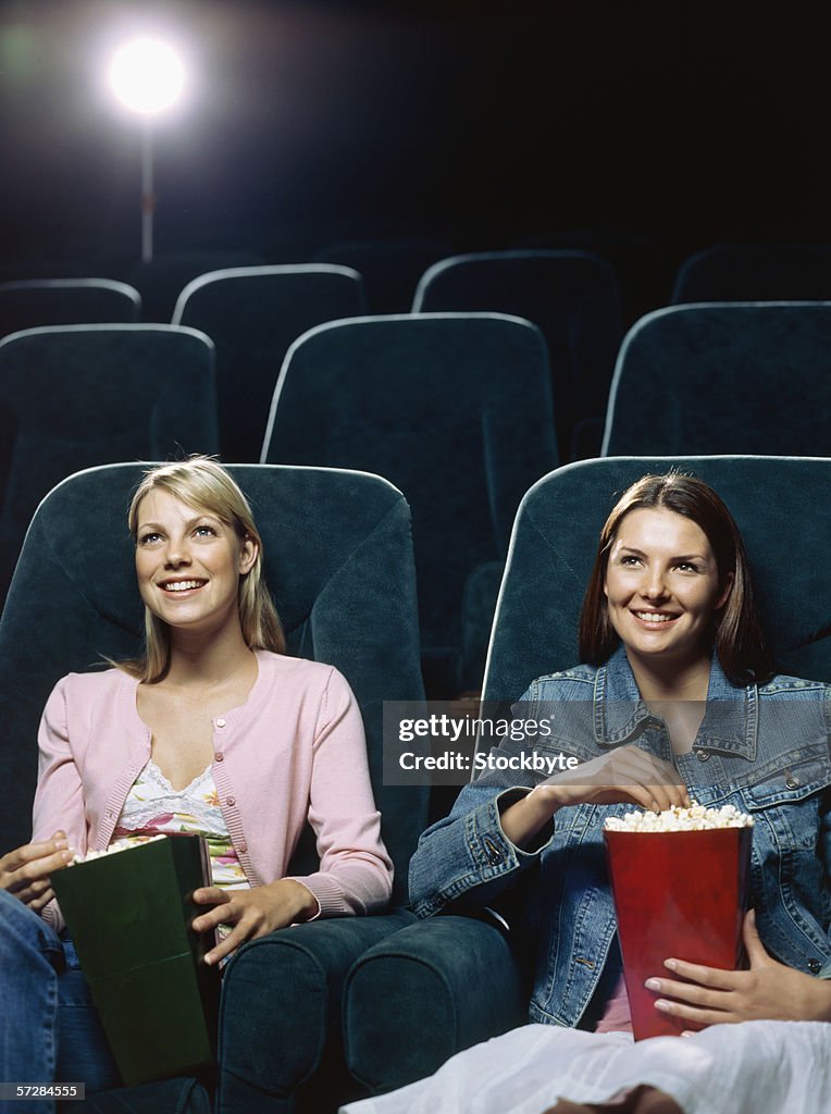 Two young women watching movie in a movie theatre