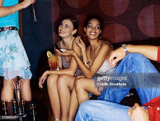 unseen man looking at three young women drinking cocktails in bar - 4 cocktails stockfoto's en -beelden
